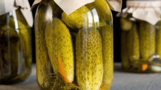 A container with pickled cucumbers enclosed with a white cloth