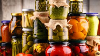 Glass jars filled with homemade pickled vegetables (cucumbers, squash, chilies, tomatoes, and beans)