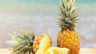 Whole and sliced pineapple isolated on the wooden table