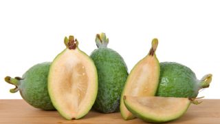 Half pineapple-guava fruit on a plain table with white background