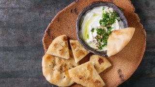 Middle eastern lebanese cream cheese dip with olive oil, salt, herbs served with traditional pita bread on terracotta plate
