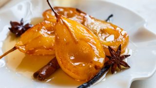 Poached pears with spices in syrup on a white plate