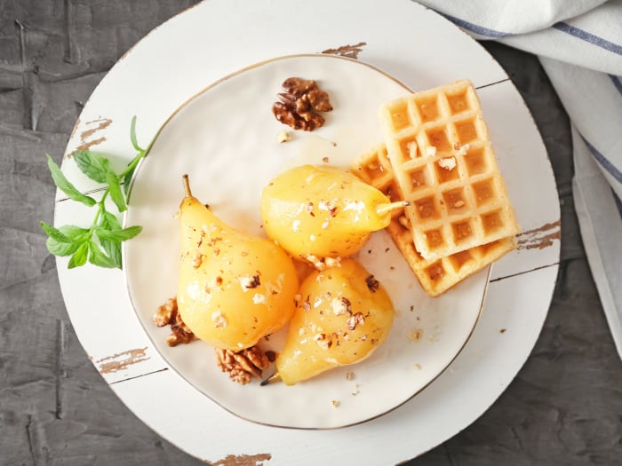 Delicious poached pears in wine and waffles on a plate