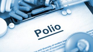 a document titled polio on a writing pad surrounded with syringe, capsule, stethoscope, and pills