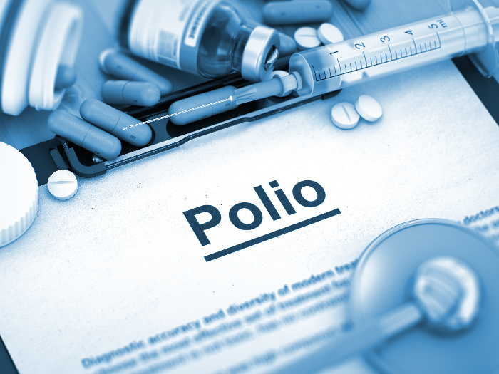 a document titled polio on a writing pad surrounded with syringe, capsule, stethoscope, and pills