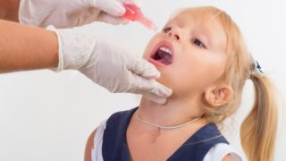 a small girl receiving an oral vaccine