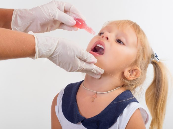 a small girl receiving an oral vaccine