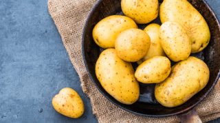 A pan filled with boiled potatoes on a grey background