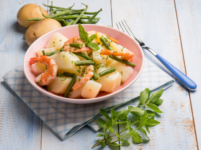 bowl of potato salad topped with herbs