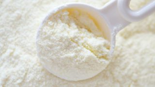 Extreme close-up of powdered milk with a plastic spoon.