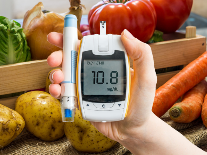 Person holding a reading meter in front of a vegetable carton