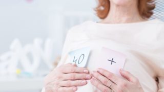 Pregnant woman with note cards depicting plus 40