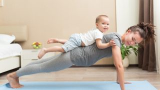 Pregnant woman doing fitness exercises in a room with her child