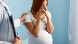A pregnant woman with her hands over her face