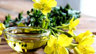 Primrose oil in an ingredient bowl with primrose flowers aside