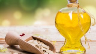 Pumpkin seed oil in a bottle surrounded by pumpkin seeds