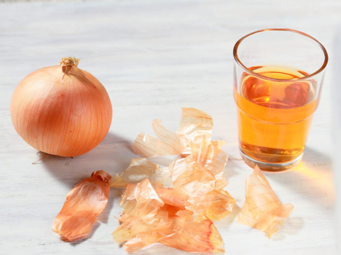 Quercetin in a glass with a whole onion and onion peels