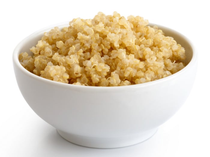 A bowl of cooked quinoa in a white bowl with white background