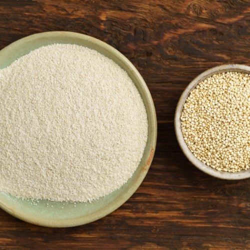 Quinoa and quinoa flour in small bowls on a wooden counter