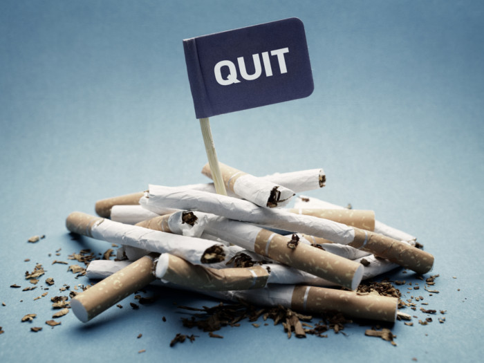 A poster of a quit smoking flag on top of a pile of cigarettes