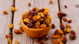 A small bowl of raisins on a wooden table