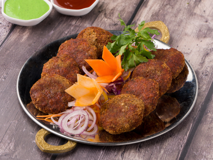 Mutton kebab pieces on a plate decorated with salad and served with sauces