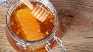 Glass jar with honeycomb and fresh raw honey