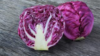 Whole and halved red cabbage on a wooden table