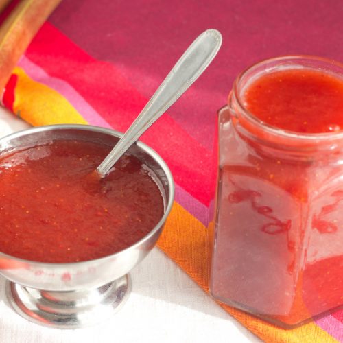 Rhubarb and strawberry classic jam in a jar on a red background