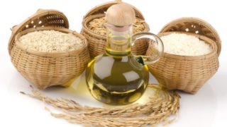 A bottle of oil placed in front of baskets of rice.