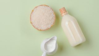 Rice milk in a round serving jar and bottle with rice grains in a soft brown bowl