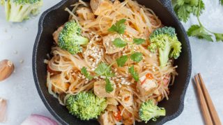 Fried rice noodles with tofu and vegetables in cast iron frying pan