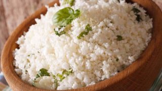 Cauliflower rice or grated cauliflower with basil leaves, in a bowl