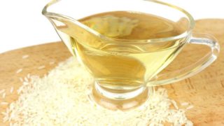 A cup of rice vinegar on top of scattered rice