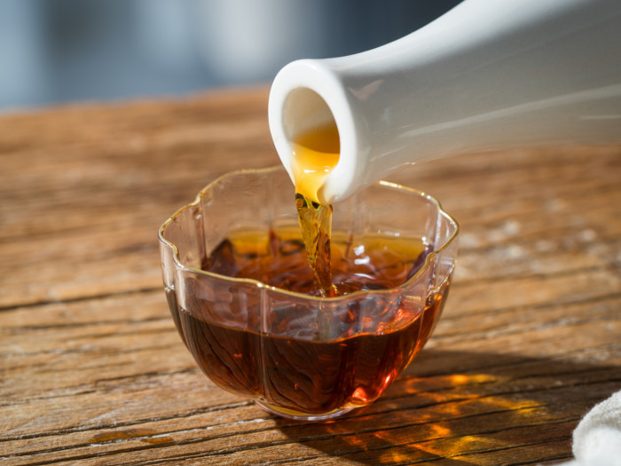 Rice wine vinegar pouring out of a white bottle into a glass bowl