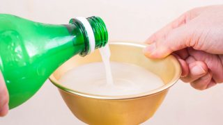 Rice wine being poured from a green bottle into a gold colored bowl