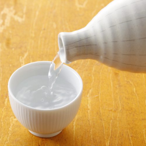 Clear liquid being poured into a small cup from a white bottle