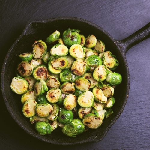 Homemade Brussels Sprouts roasted with olive oil against a black slate background