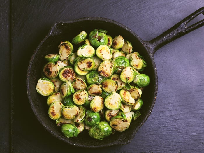 Homemade Brussels Sprouts roasted with olive oil against a black slate background