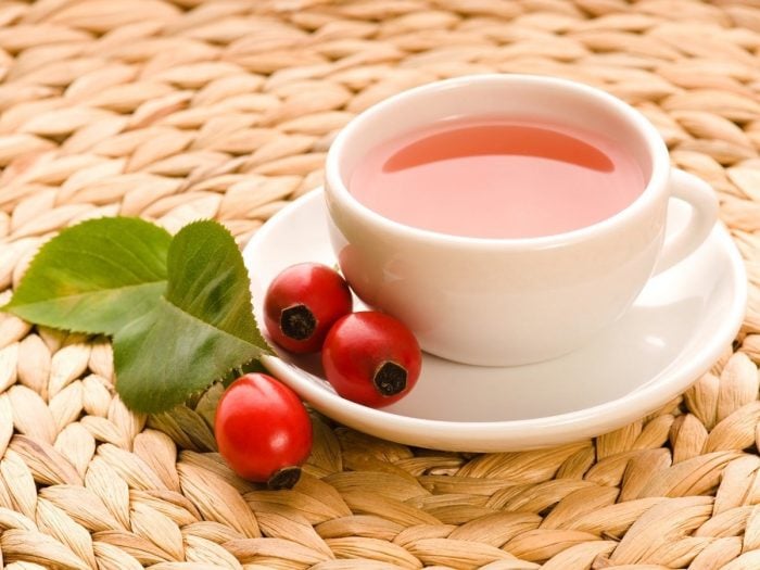 Rosehip tea in a cup and a couple of rosehips on a saucer