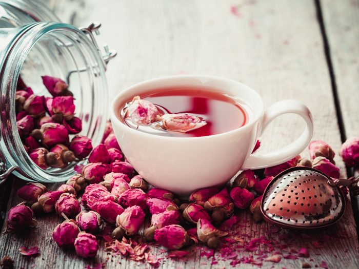 A cup of rose tea with rose buds around