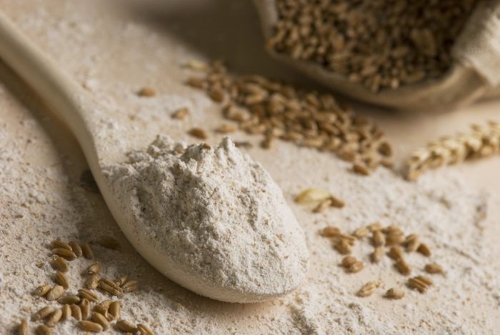 Rye flour on spoon and rye grain in canvas bag