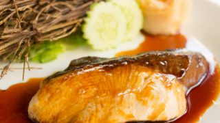 Close up of Asian style sablefish with hoisin sauce on a white plate