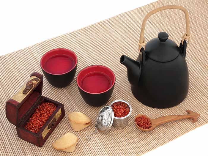 Saffron tea, saffron spice in tins, and a black teapot on a table