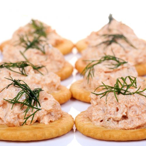 Salmon spread on cracker cookies on white background