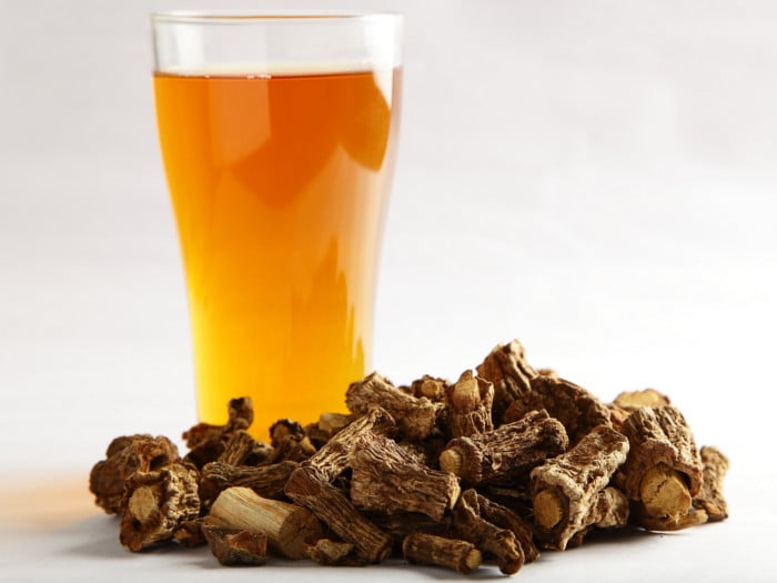 A close-up shot of sarsaparilla tea kept next to the sarsaparilla root from which it is made