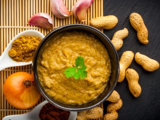 sataysauce Delicious Satay sauce placed in a bowl atop a table, next to groundnuts and onions