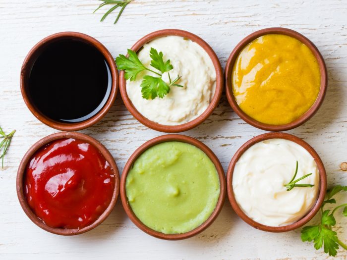 Different sauces like soy sauce, ketchup, etc in bowls garnished with cilantro