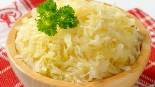 A wooden bowl of sauerkraut on a red kitchen napkin