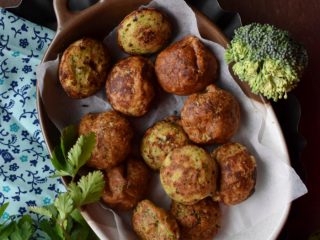 Flatline view of a tray of muffins with a broccoli head and coriander leaves kept on either side